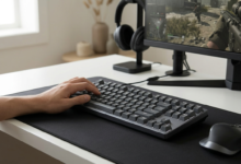 A sleek gaming desk setup featuring a high-performance mechanical keyboard with subtle RGB backlight, next to a gaming mouse on a dark desk mat.